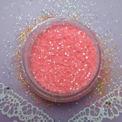 Frasco redondo com glitter rosa sobre superfície lilás com padrão rendado branco e brilhos