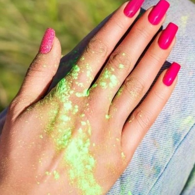 Mão com unhas rosa vibrante e glitter com pó verde fluorescente, texto '378 DELULU' e 'DOPAMINA GEL POLISH'.