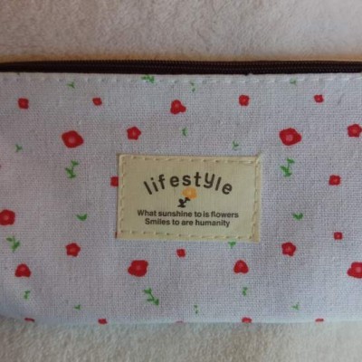 Estojo branco com flores vermelhas pequenas e etiqueta com texto em inglês