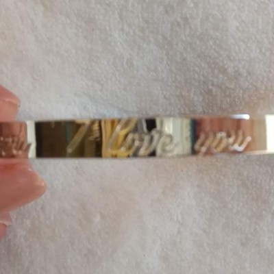 Pulseira metálica prateada com gravação 'LOVE' repetida.