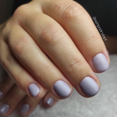 Unhas pintadas de verniz lilás claro em mãos com unhas curtas