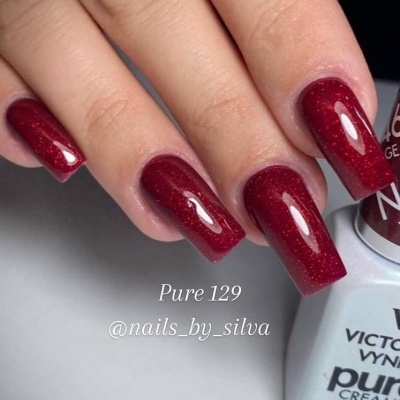 Unhas com verniz gel vermelho brilhante próximas a frasco branco de verniz VICTORIA VYNN Pure 129