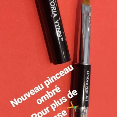 Pincel para unhas com cabo preto e tampa preta sobre fundo vermelho