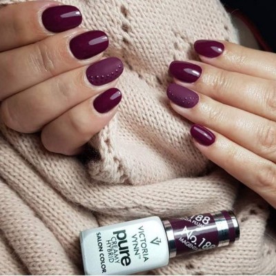 Mãos com unhas pintadas de vermelho vinho com pontos e frasco de verniz Victoria Vynn Pretty Pure Nº 188