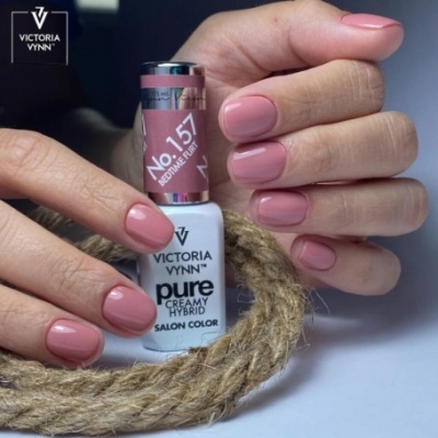 Mãos femininas com unhas rosa cremoso segurando verniz VICTORIA VYNN No.157