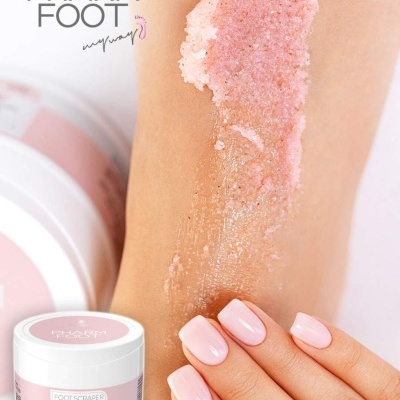 Esfoliante rosa e branco aplicado no pé com unhas pintadas, próximo de recipiente com rótulo PHARM FOOT.