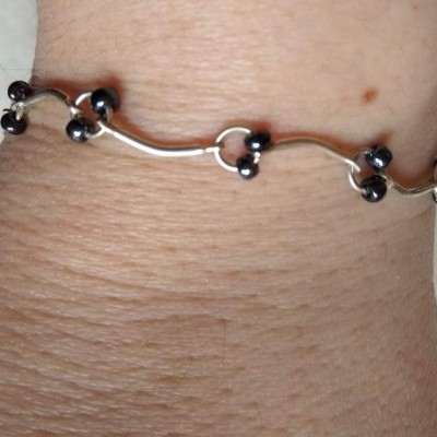 Pulseira prateada com esferas pretas no pulso