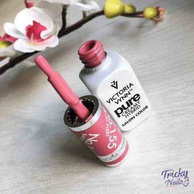 Esmalte de unhas rosa Victoria Vynn Pure com pincel sobre superfície cinzenta e flores ao fundo