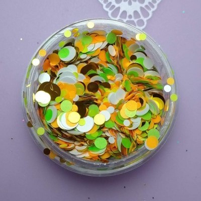 Frasco de confetes coloridos metalizados sobre superfície lilás com padrão branco