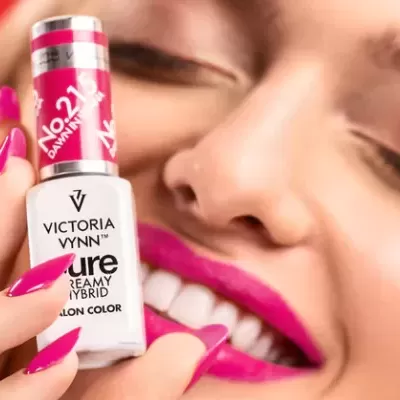 Frasco de verniz de unhas Victoria Vynn com unha pintada rosa vibrante e lábios cor de rosa.