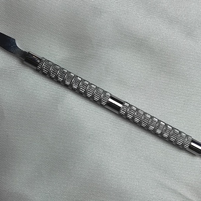 Espátula dupla metálica texturizada em fundo branco