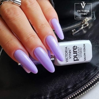 Unhas compridas com verniz lilás brilhante segurando verniz Victoria Vynn sobre couro preto.