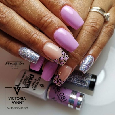 Unhas decoradas com verniz lilás, glitter e padrão de animal print, frascos de verniz Victoria Vynn ao fundo