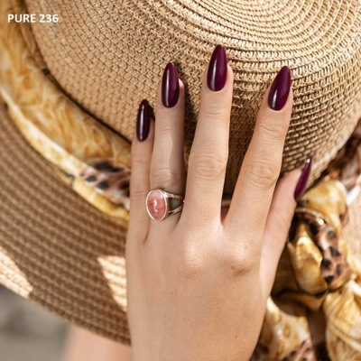 Mão com unhas bordô e anel com pedra rosa sobre chapéu de palha e lenço com padrão leopardo