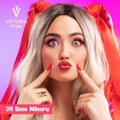Mulher com unhas e lábios vermelhos, cabelo loiro com laços vermelhos, texto Victoria Vynn e 311 Rose Minoru
