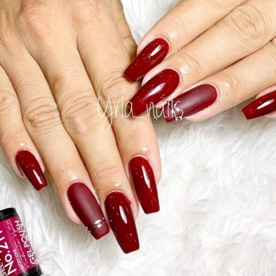 Unhas postizas vermelhas em fundo branco com frascos de verniz gel