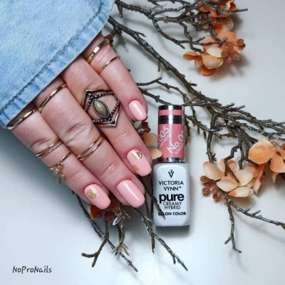 Mãos femininas com unhas pintadas de verniz rosa claro segurando uma garrafa de verniz Victoria Vynn Pure Creamy Hybrid rosa