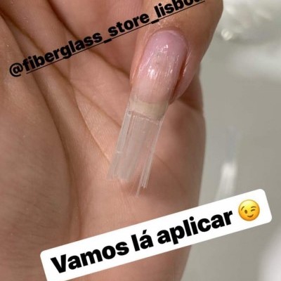 Unha com extensão transparente de fibra de vidro numa mão