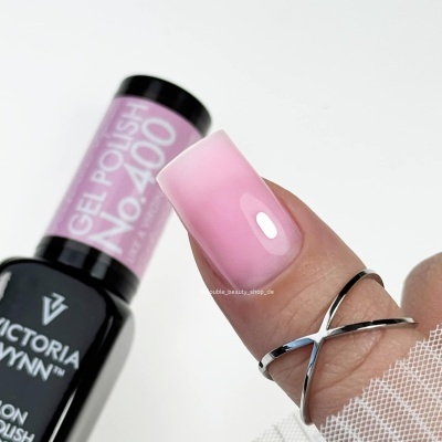 Unha com verniz gel rosa e anel prateado junto a frasco de verniz