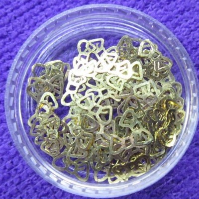 Recipiente transparente com pequenos objetos metálicos dourados triangulares sobre tecido roxo