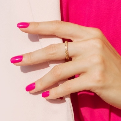 Mão feminina com anel dourado e unhas pintadas de rosa forte
