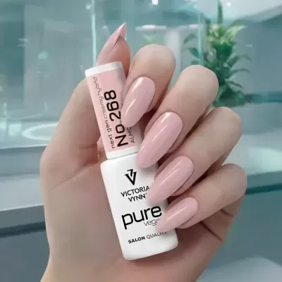 Frasco de verniz de unhas segurado por mão feminina com unhas rosa claro.