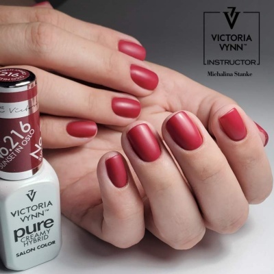 Unhas pintadas de vermelho fosco com verniz gel Victoria Vynn e frasco do produto ao lado.