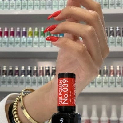 Frasco de verniz gel preto Victoria Vynn com mão a segurar exibindo unhas vermelhas