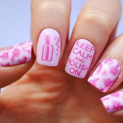 Unhas com verniz rosa claro e desenhos rosa escuro, incluindo texto 'KEEP CALM AND POLISH ON'