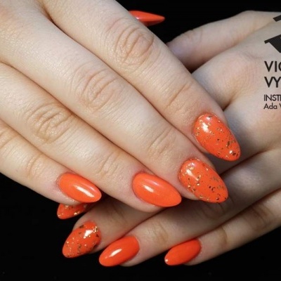 Mãos femininas com unhas pintadas de laranja brilhante e alguns brilhos dourados