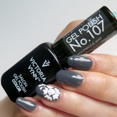 Mão com unhas pintadas a cinzento escuro e branco segurando verniz gel Victoria Vynn