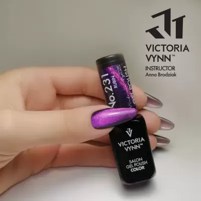 Frasco de verniz de gel preto VICTORIA VYNN No.231 RUBIN com unha pintada de roxo brilhante segurando o frasco.