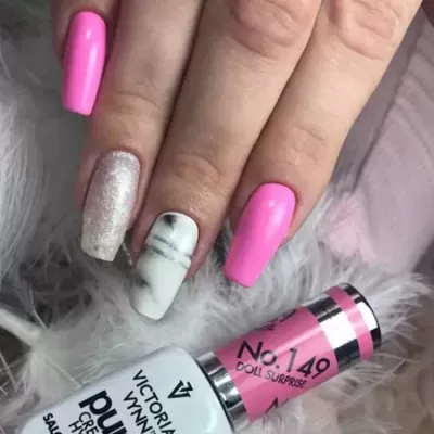 Unhas com verniz rosa, glitter e marmoreado ao lado de frasco de verniz