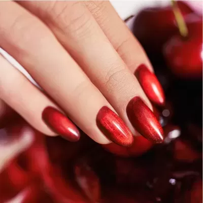 Unhas ovais pintadas de vermelho metálico brilhante em mão feminina