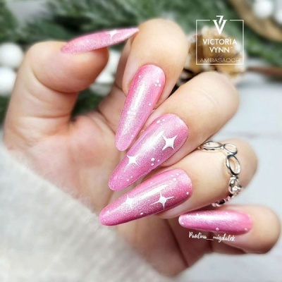 Mãos com unhas rosa brilhantes decoradas com estrelas brancas e anel prateado