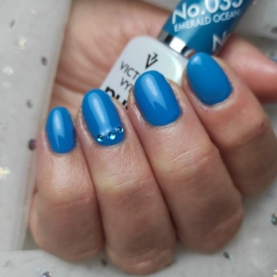 Unhas pintadas de azul com verniz Victoria Vynn n.º 033 Emerald Ocean e strass azuis.