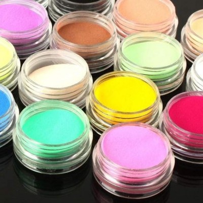 Recipientes transparentes com pós coloridos variados sobre superfície preta