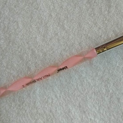 Pincel de unhas rosa com dois lados sobre toalha branca