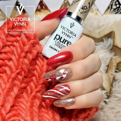 Unhas manicura vermelha e dourada com decoração Natalina segurando verniz Victoria Vynn
