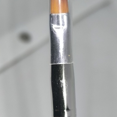 Pincel de maquilhagem com cabo azul e cerdas castanhas coberto por tampa transparente