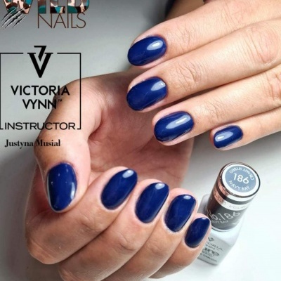 Unhas pintadas de azul-marinho com frasco de verniz e texto promocional ao fundo