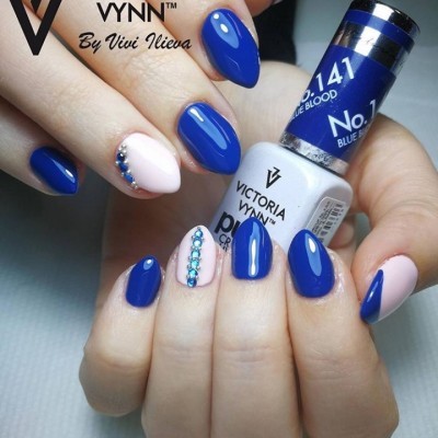 Unhas pintadas em azul e rosa claro com pedras decorativas e frasco de verniz VICTORIA VYNN