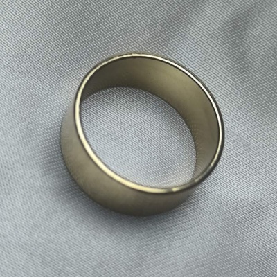 Anel prateado liso sobre tecido cinzento