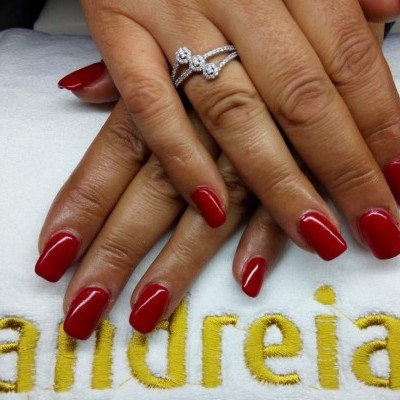 Mãos com unhas vermelhas e anel prateado sobre toalha branca bordada