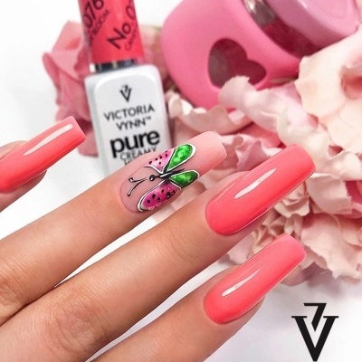 Unhas compridas cor de coral com unha decorada com borboleta e frasco de verniz Victoria Vynn no fundo