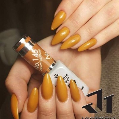 Unhas pintadas de mostarda cremosa com embalagem do verniz Victoria Vynn