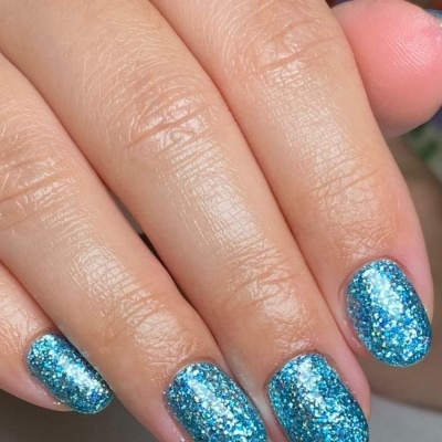 Mão com unhas pintadas de azul com glitter prateado