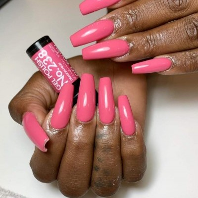 Unhas compridas com verniz rosa e frasco de verniz gel cor-de-rosa