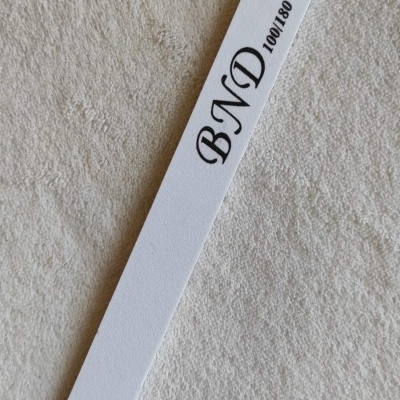 Lima de unhas branca com texto BND 100/180 sobre superfície clara