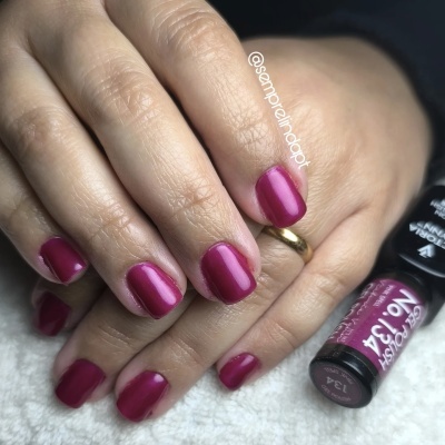 Unhas curtas pintadas com verniz rosa escuro ao lado de frasco de verniz Corfashion nº 134